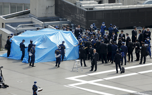 Ճապոնիայում անվտանգության աշխատակիցները վրանով փակել են երկրի վարչապետի գրասենյակի վրա իջեցված փոքր քաղաքացիական ԱԹՍ-ն, որը կրել է ռադիոակտիվ նյութ, ապրիլ 2015 (արխիվ)